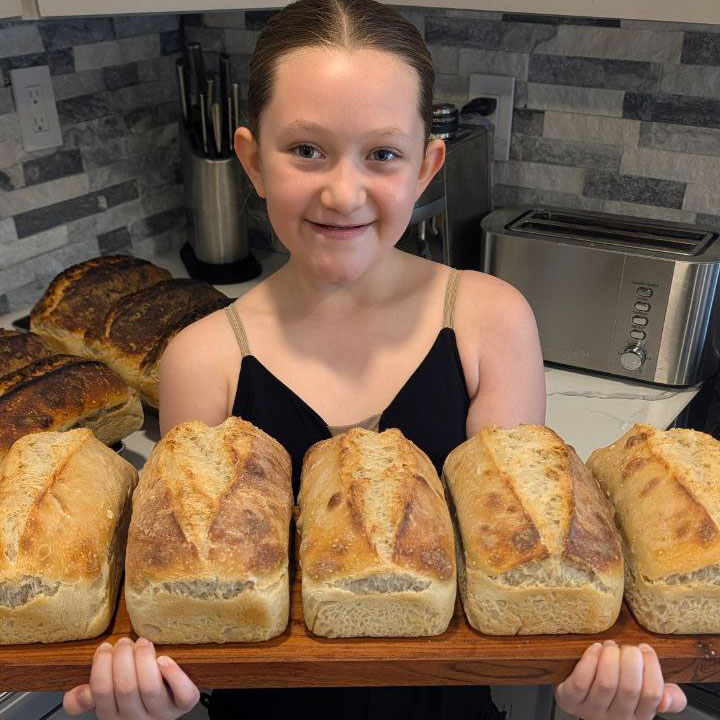 Our young baker proudly holding freshly baked sourdough loaves
