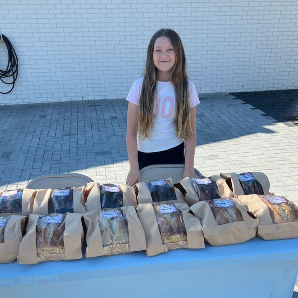 Meilani standing behind a table full of packaged sourdough loaves
